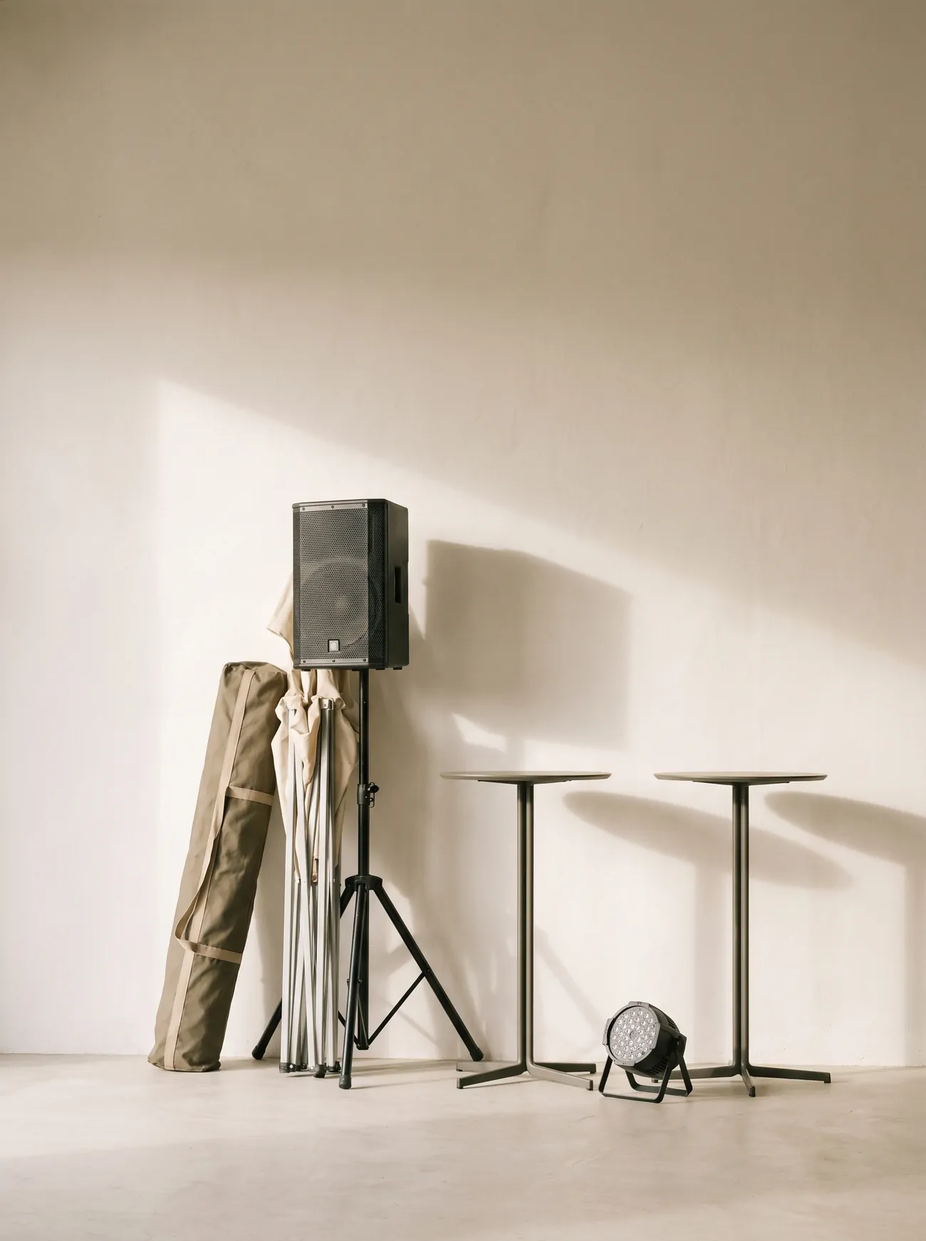 A PA speaker, a folded party tent, standing tables and a stage light