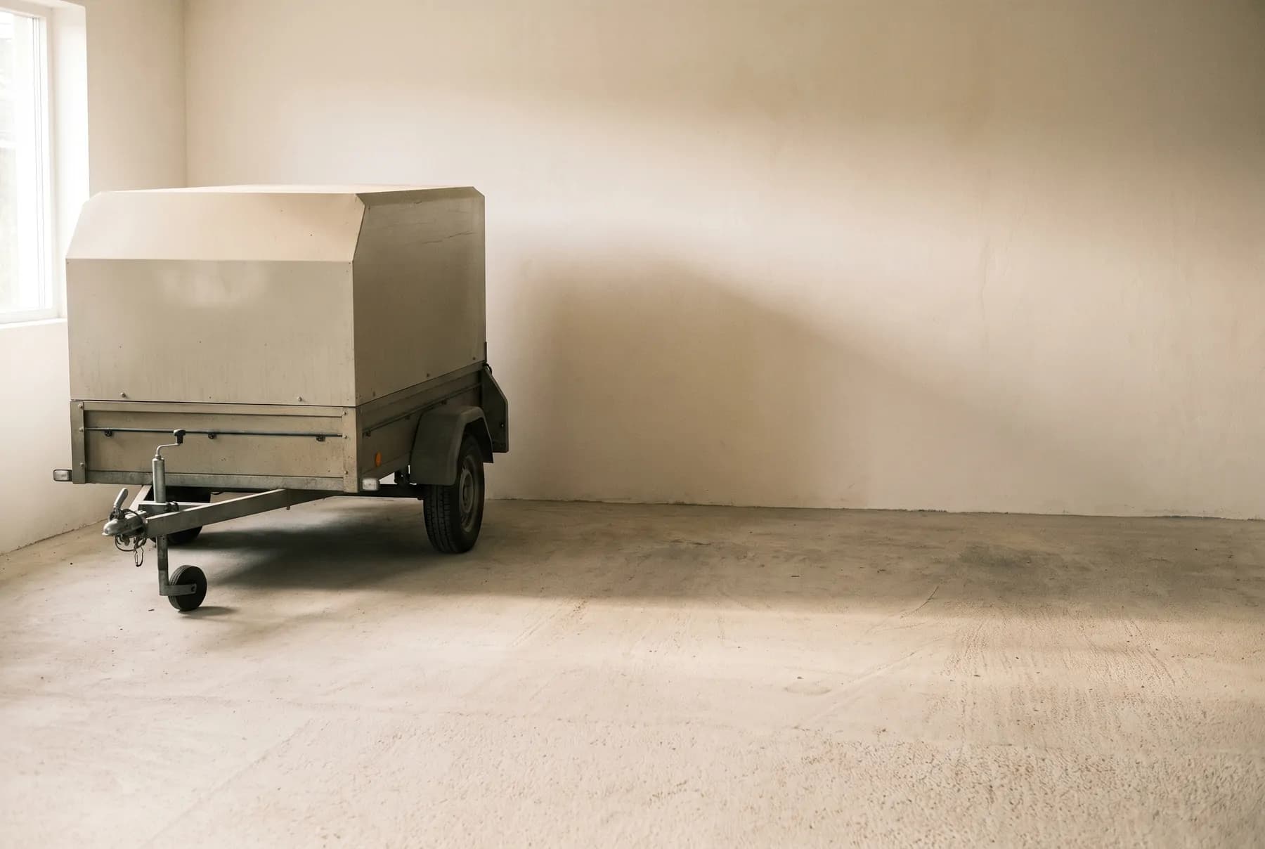 A small covered box trailer parked in a clean garage